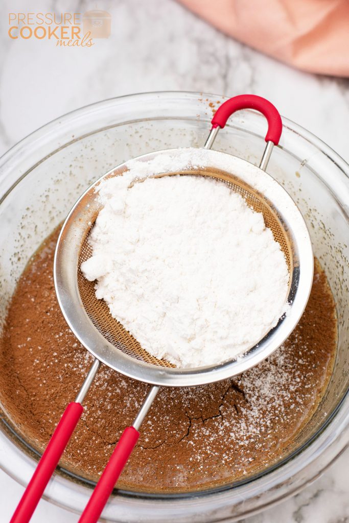 sifting powdered sugar over bowl of brownie batter