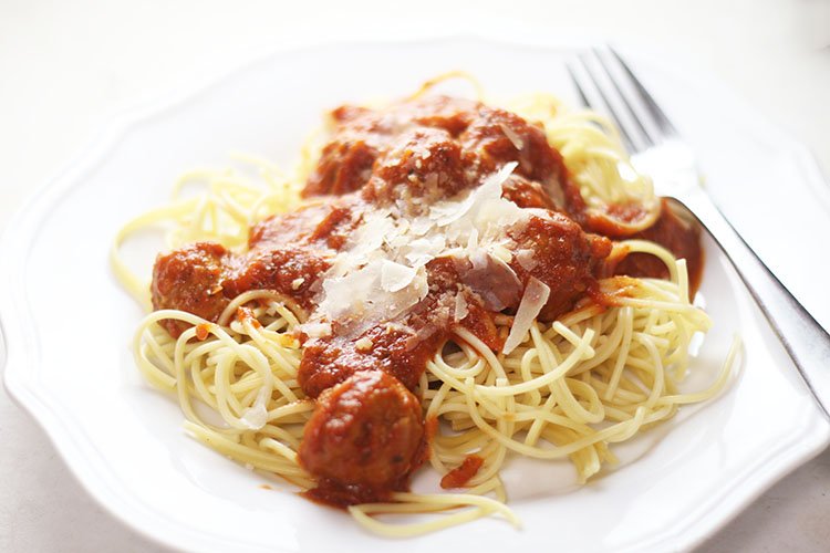 Easy Instant Pot Spaghetti & Meatballs with shaved parmesan on a white plate with a fork