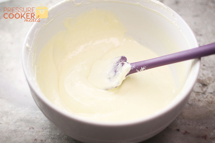 Instant Pot Chocolate Chip Cookie Dough Cheesecake batter in mixing bowl with silicone spatula
