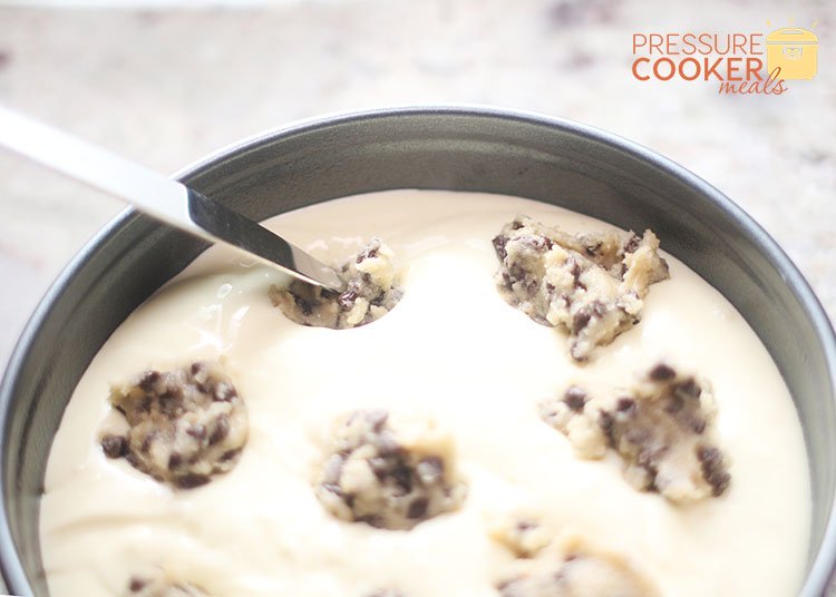 pressing cookie dough into Instant Pot Chocolate Chip Cookie Dough Cheesecake batter in springform pan