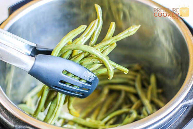 Instant Pot Southern Green Beans with bacon and onion being dipped from pot
